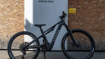 A mountain bike parked against a wall with a sign that reads 'Einfach RADL IN DEN STALL STELLEN'.