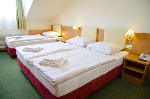 Habitación de hotel con dos camas, cada una con toallas ordenadas, lámparas de noche y un teléfono en la mesita.