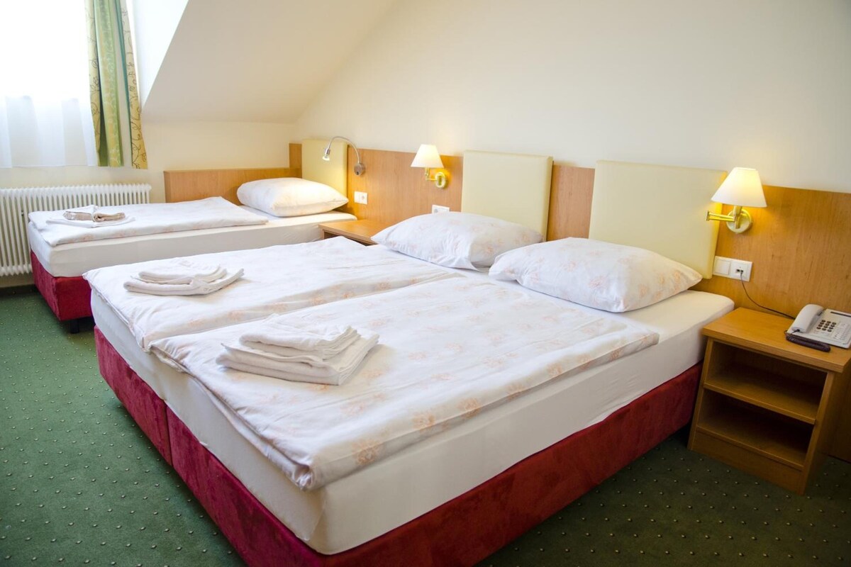 A hotel room with two beds, each with neatly folded towels, bedside lamps, and a telephone on the nightstand.
