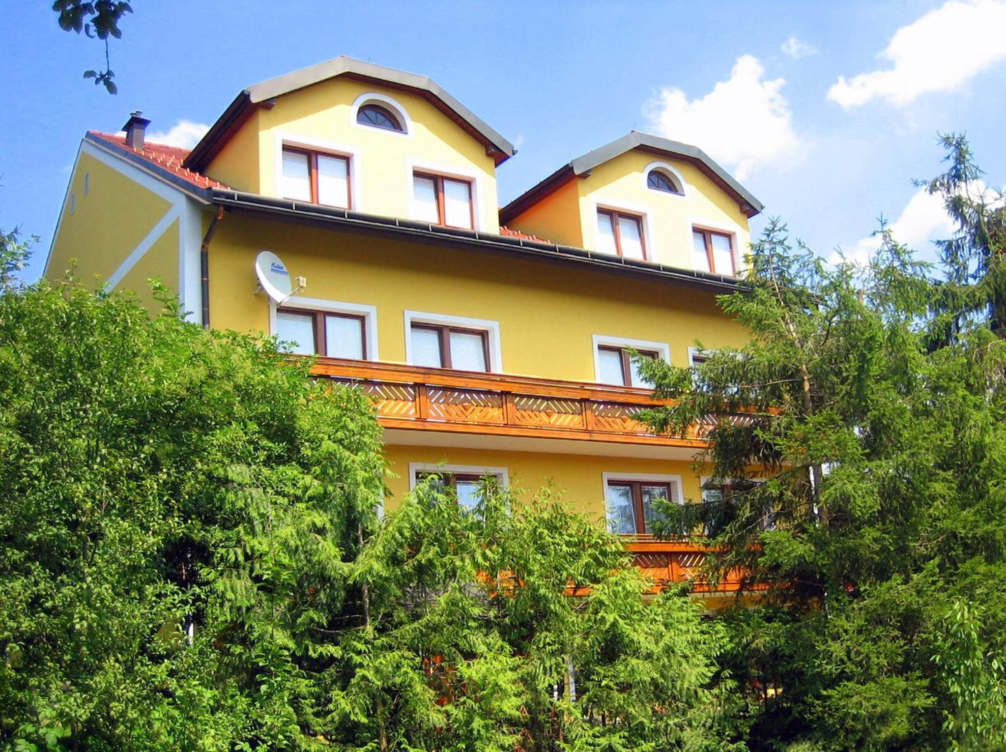 A two-story building with a yellow facade, multiple windows, and a balcony with a railing.