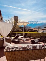 Una terraza con asientos exteriores, un toldo y vistas a las montañas.