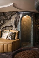 Un dormitorio con pared de piedra, un rincón de estar circular y un rincónado con mosaicos.