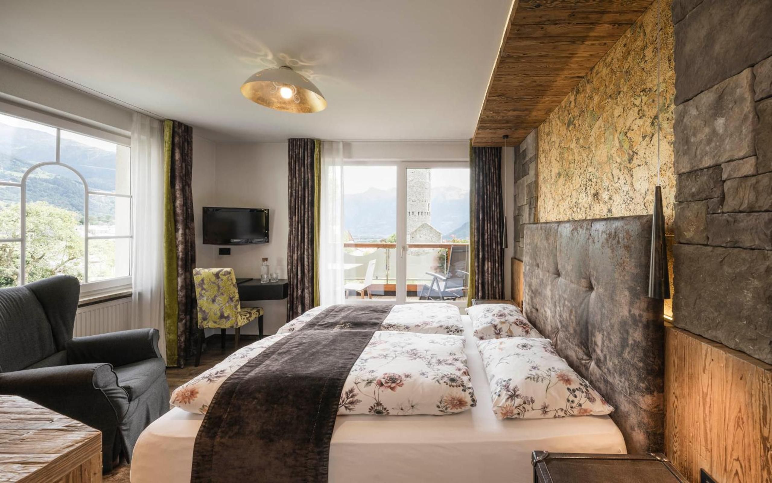 Una camera d'albergo con un letto grande, una scrivania, una sedia e un televisore.