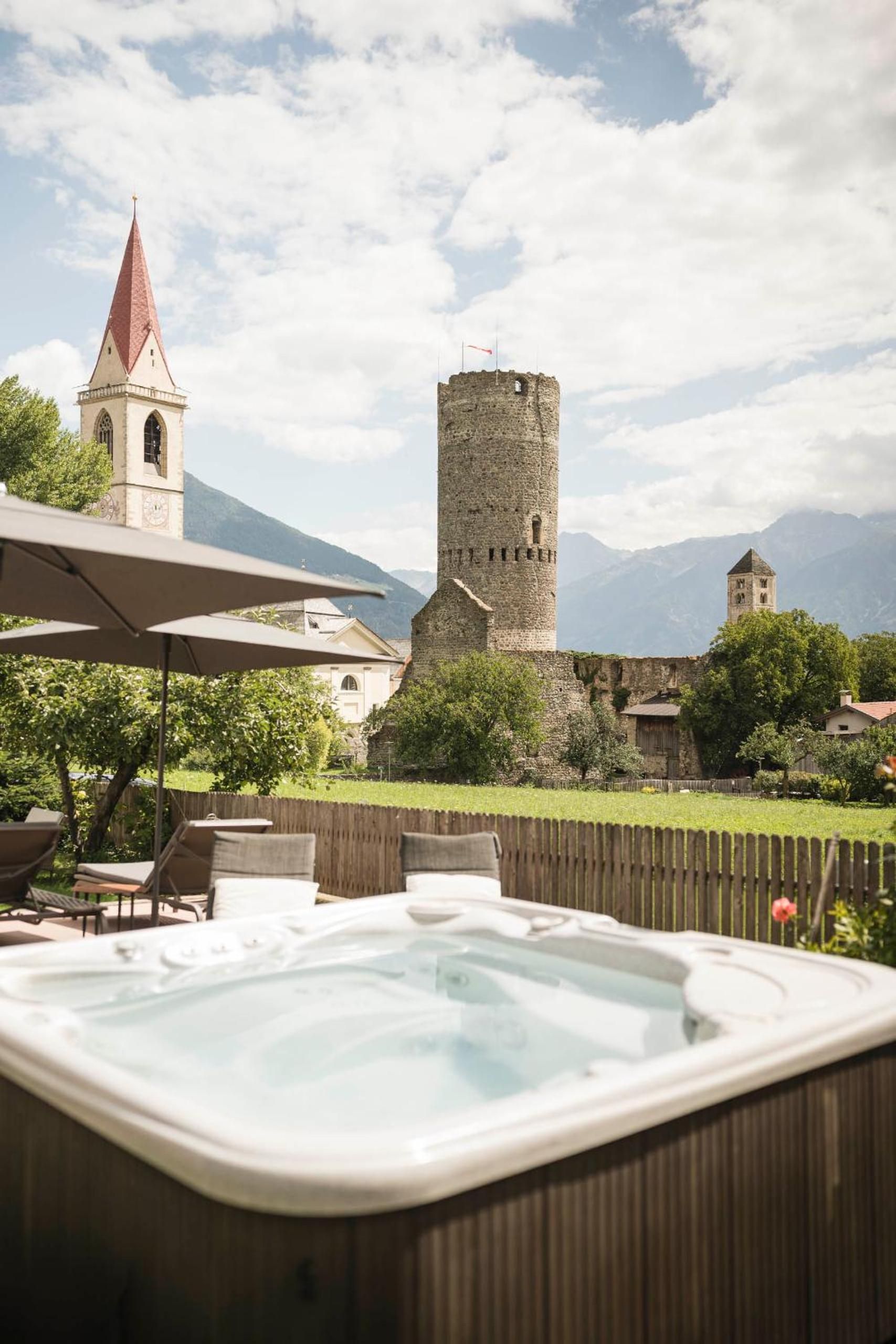 Un jacuzzi en un patio trasero con un castillo e iglesia al fondo.