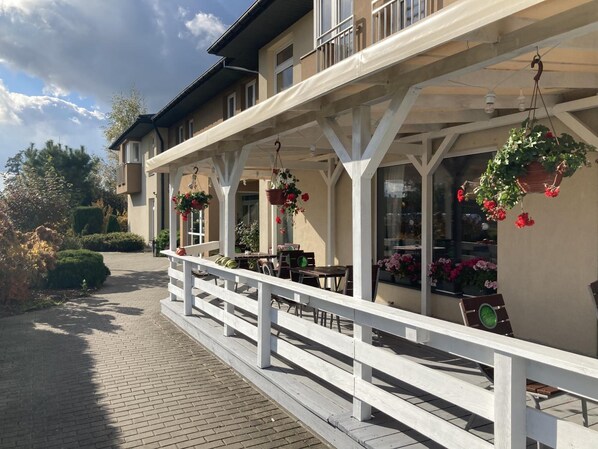 A covered outdoor seating area with white railings and hanging flower baskets.
