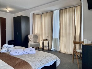 A hotel room with a bed, a chair, a desk, a wardrobe, and a window with curtains. - Hotel Solec (Gora Kalwaria)