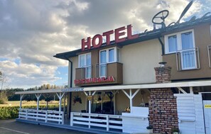A hotel with a sign reading 'HOTEL RESTAURACJA' and a covered outdoor seating area.