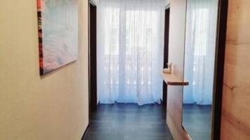 Un pasillo con piso de madera, un espejo grande a la derecha y un cuadro a la izquierda.