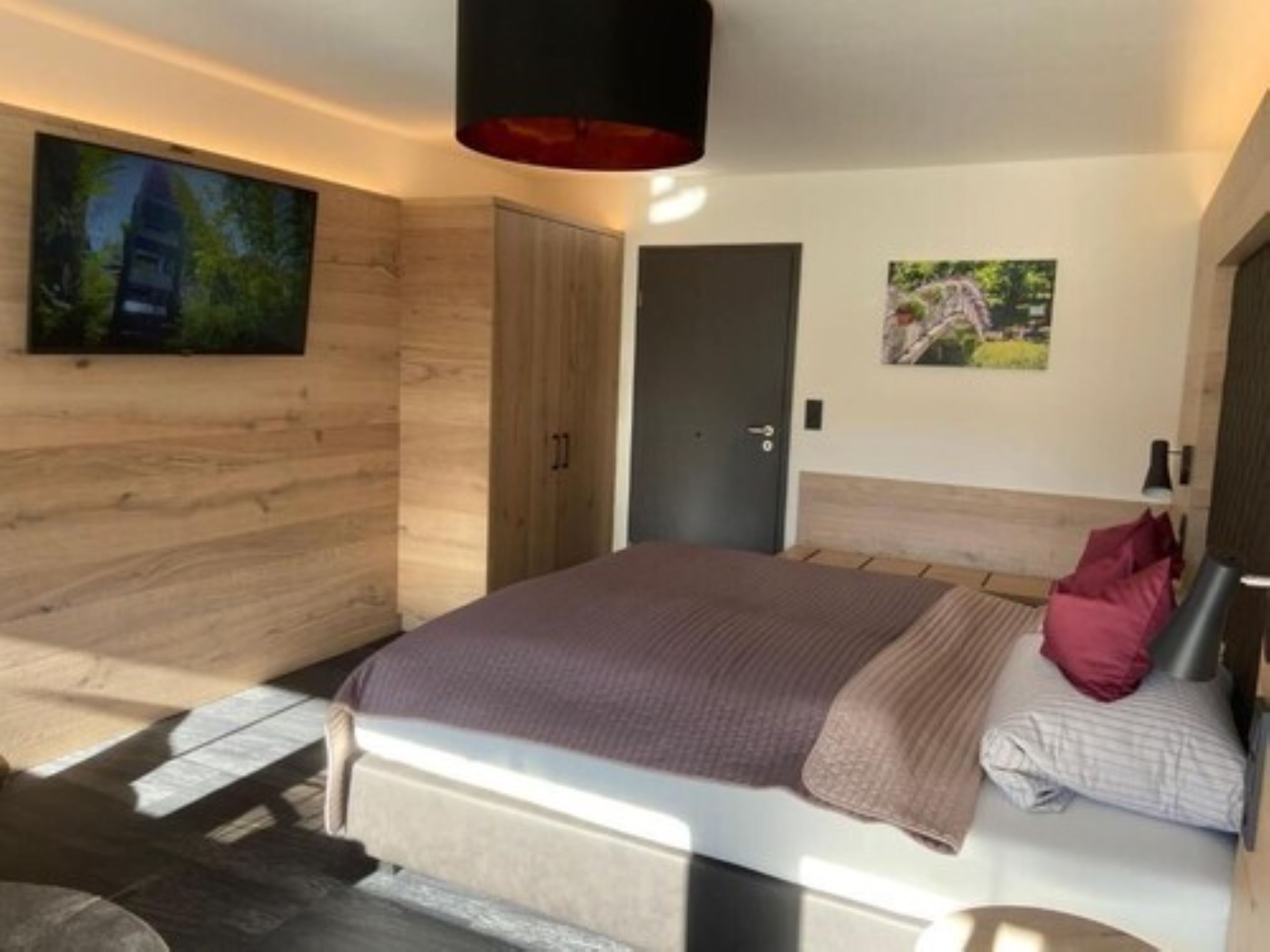 Een moderne slaapkamer met een groot bed, houten wanden en een deur.