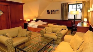 Habitación de hotel con una cama, dos sofás, una mesa de centro y un escritorio con lámpara.