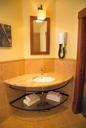 A bathroom with a curved sink, a mirror, a towel rack, and a wall-mounted phone. - Wawrzyniak (Zduny)