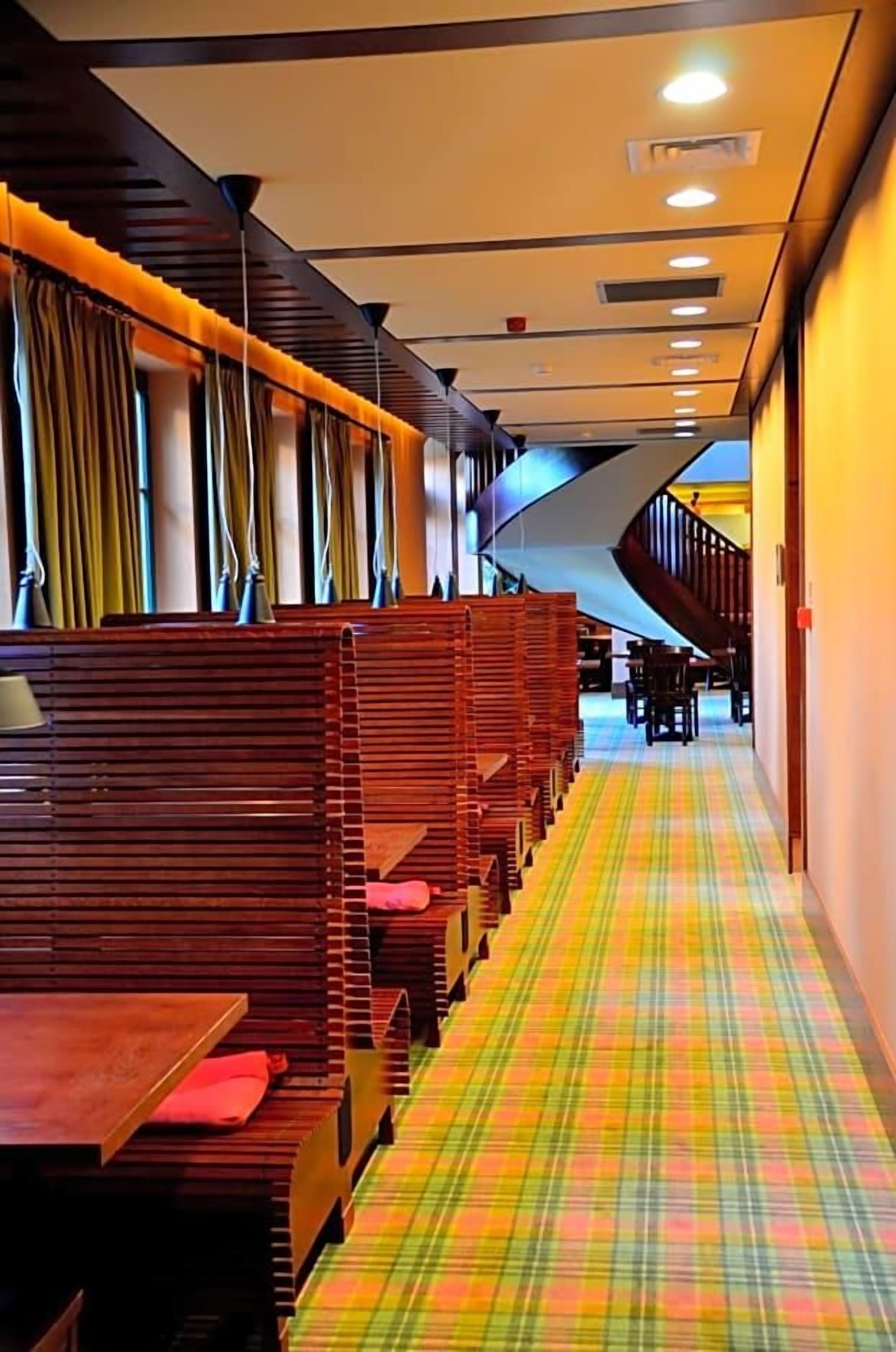 A restaurant with wooden booths, a checkered floor, and a staircase in the background.