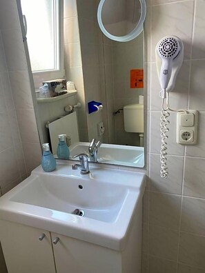 A bathroom with a white sink, mirror, and a hairdryer mounted on the wall.