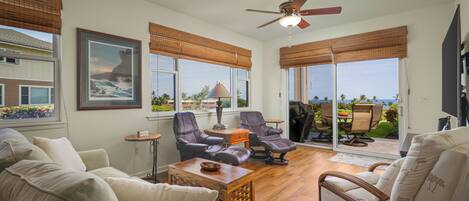 A spacious living room with a large window, a ceiling fan, and a view of the outdoors.
