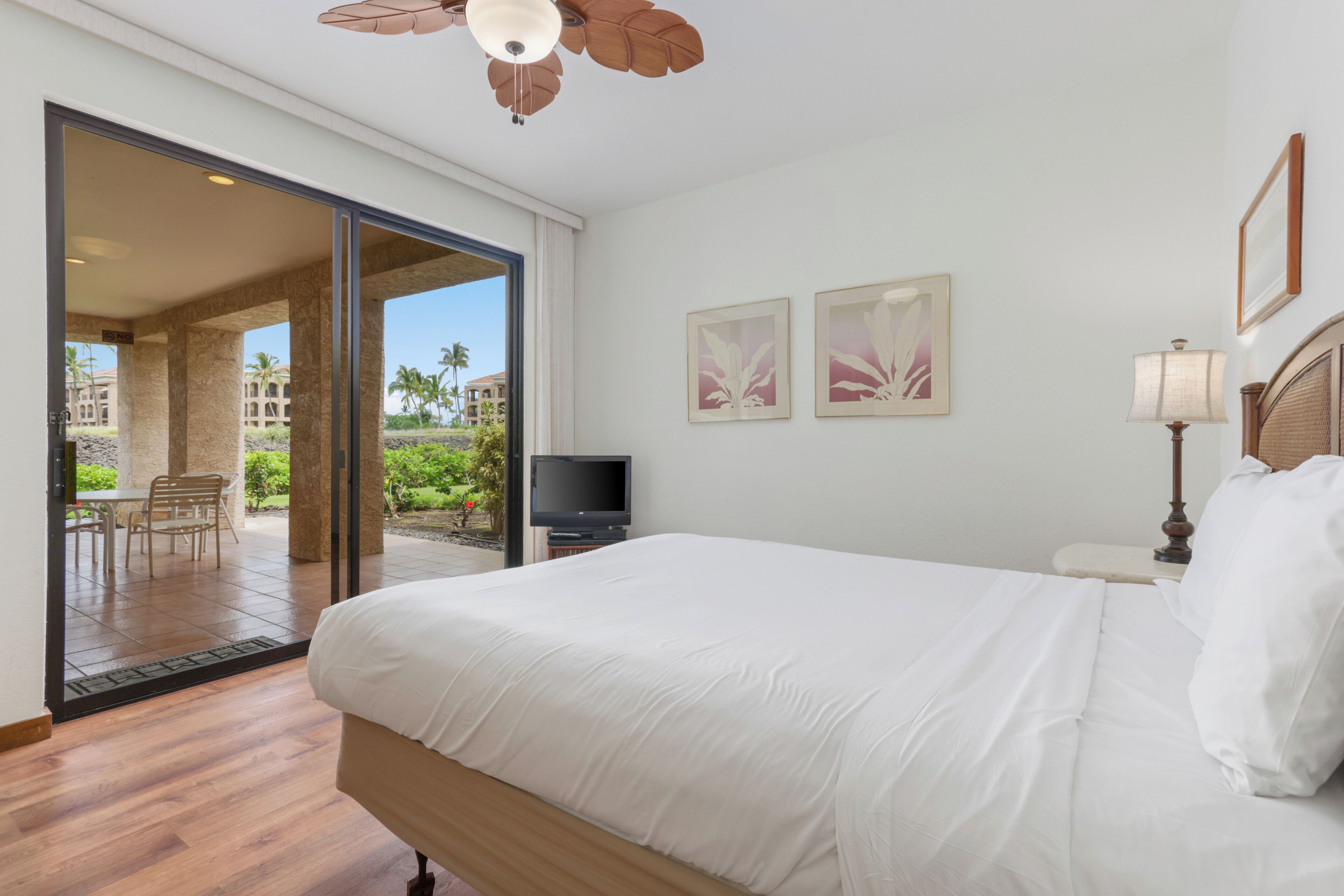 A bedroom with a bed, a television, and a view of a patio with outdoor furniture.