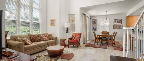 A spacious living room with a sofa, armchair, coffee table, and dining area.