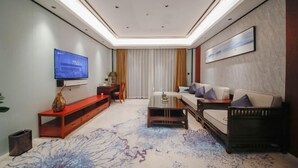 A modern living room with a flat-screen TV, a sofa, a coffee table, and a red console table. - Yue Feng Yuan Hotel (Fengkai)
