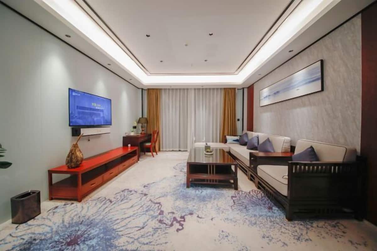 A modern living room with a flat-screen TV, a sofa, a coffee table, and a red console table.