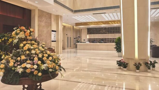 A spacious lobby with a large floral arrangement, a reception desk, and a modern ceiling design. - Yue Feng Yuan Hotel (Fengkai)
