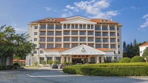 A multi-story hotel with a central entrance, a parking area, and well-maintained landscaping. - Yue Feng Yuan Hotel (Fengkai)