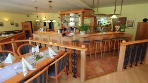 A restaurant with wooden furniture, a bar area, and hanging lights. - Residenzia Hotel Grenadier (Munster im Heidekreis)