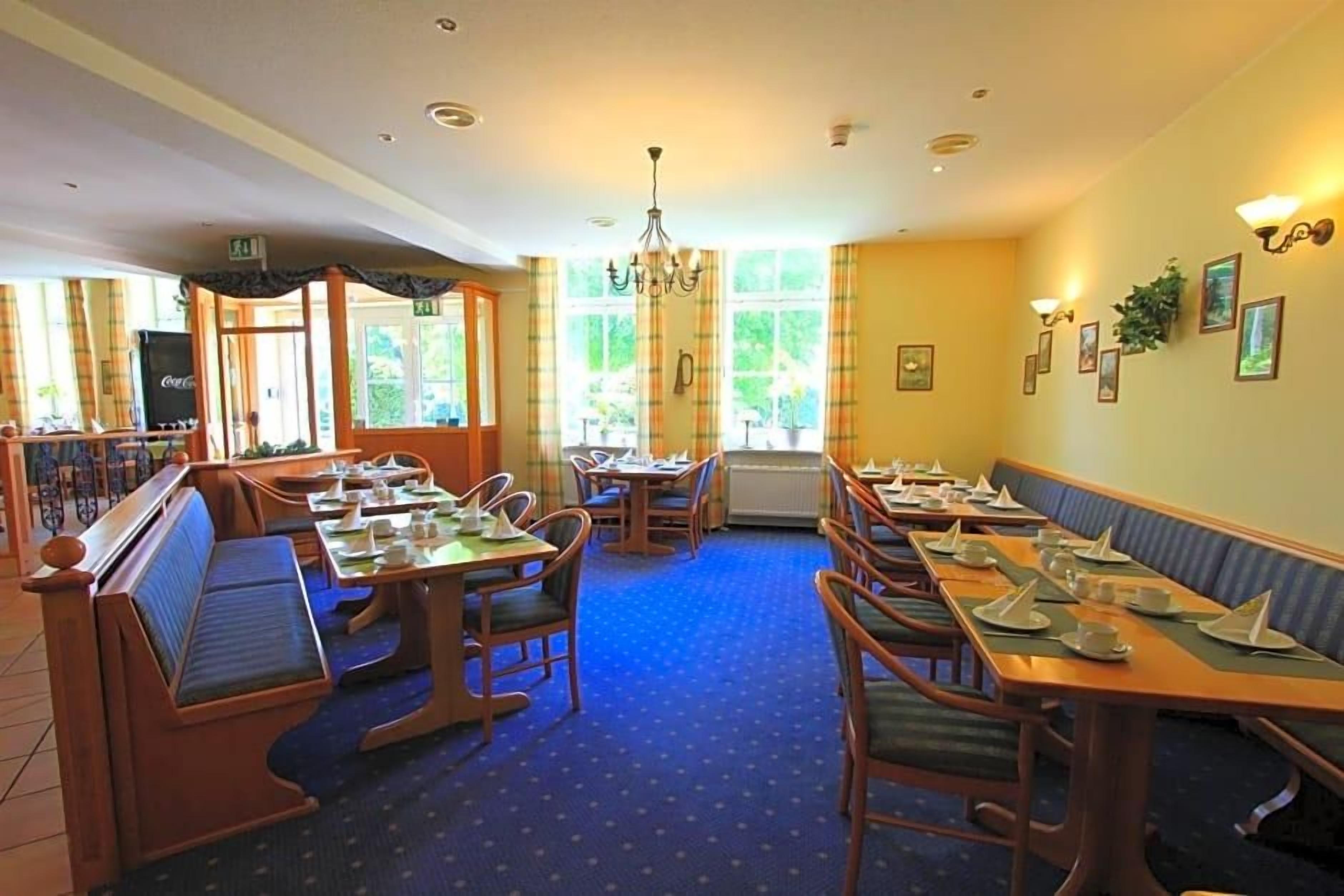 A restaurant with booths and tables, a chandelier, and framed pictures on the walls.