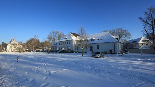 A large, snow-covered building with multiple windows and a prominent entrance. - Residenzia Hotel Grenadier (Munster im Heidekreis)