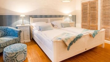 A bedroom with a bed, two nightstands, a chair, and a footstool.