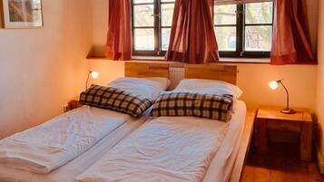 Ein Doppelbett mit Holzrahmen, zwei Nachttische mit Lampen und ein Fenster mit Vorhängen.