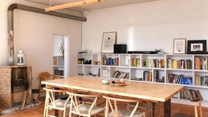 A room with a wooden table and chairs, a bookshelf filled with books, a fireplace, and a hanging light fixture. - Beijing Migrator Mountain Resort (Changping)