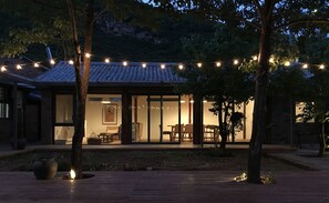 Una casa con techo de tejas, amplios ventanales y una terraza de madera.