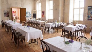 A spacious dining hall with multiple tables and chairs, large windows, and a rustic interior. - Schloss Plaue (Brandenburg an der Havel)