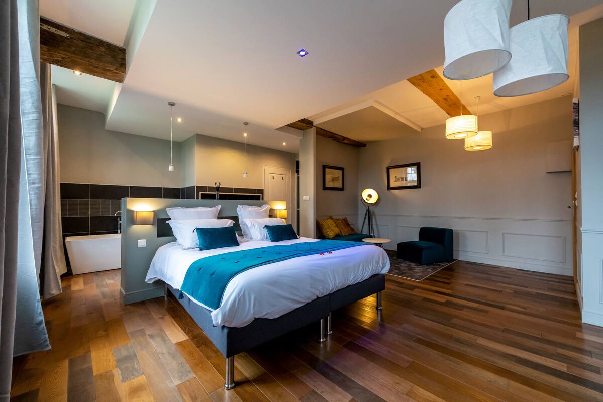 A modern bedroom with a large bed, bedside tables, a desk, and a chair.