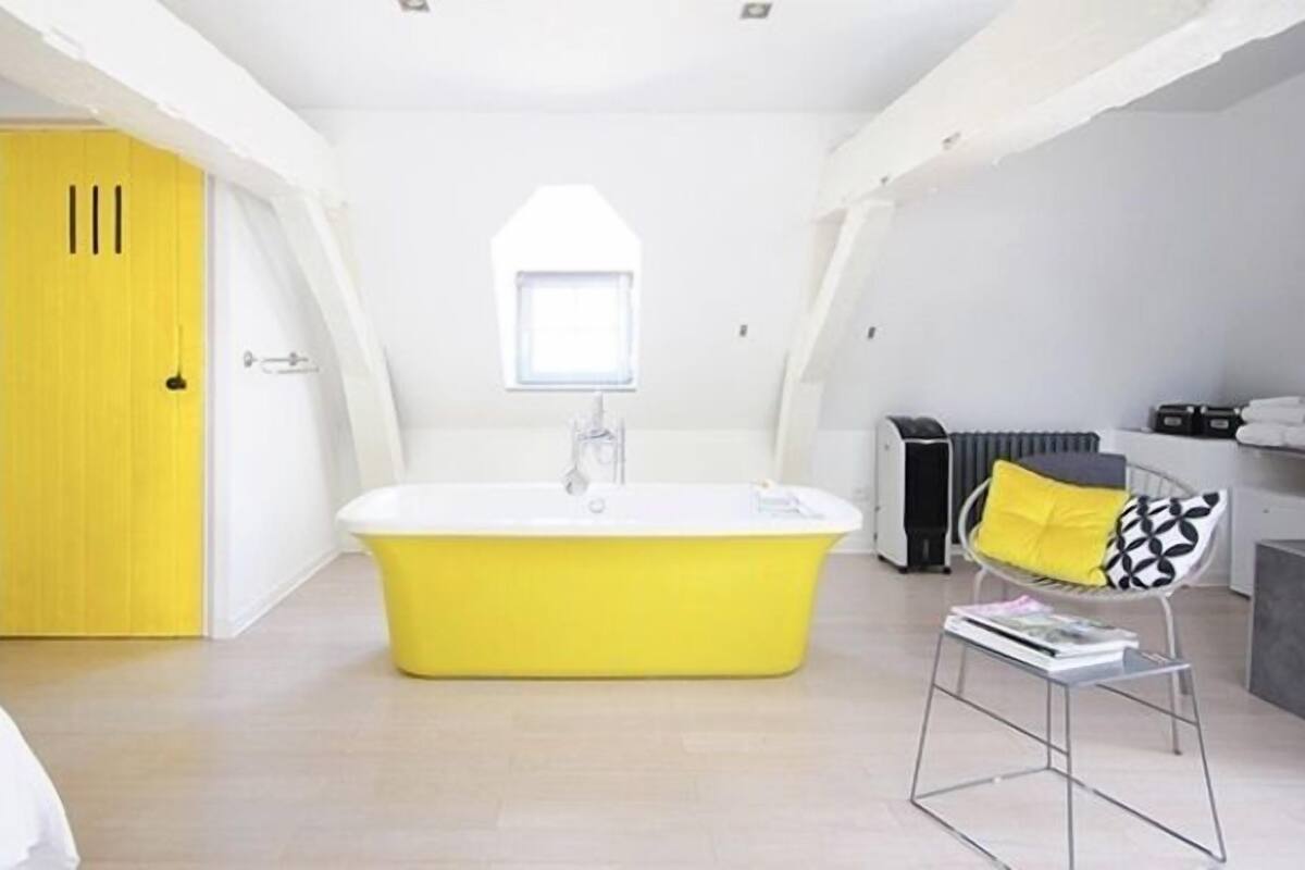 A modern bathroom with a yellow bathtub, a window, and a radiator.