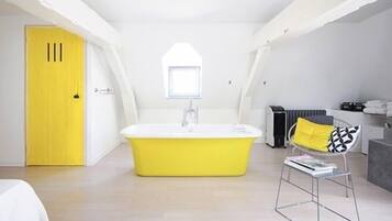 Een moderne badkamer met een geel bad, een raam en een radiator.