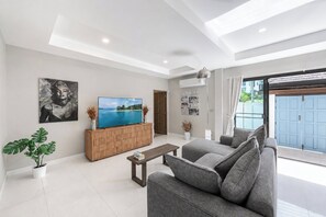 Un salon moderne avec un téléviseur à écran plat, un canapé, une table basse et une plante en pot.
