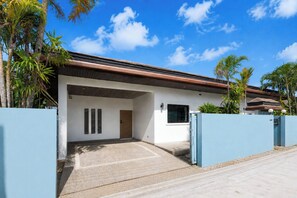 Une maison moderne dotée d’une allée couverte, d’un garage et d’une façade blanche.