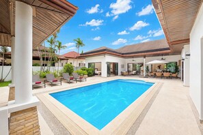 A swimming pool with lounge chairs and a covered patio area. - Boutique 3BR Pool Villa White Cove Rawai (Rawai)