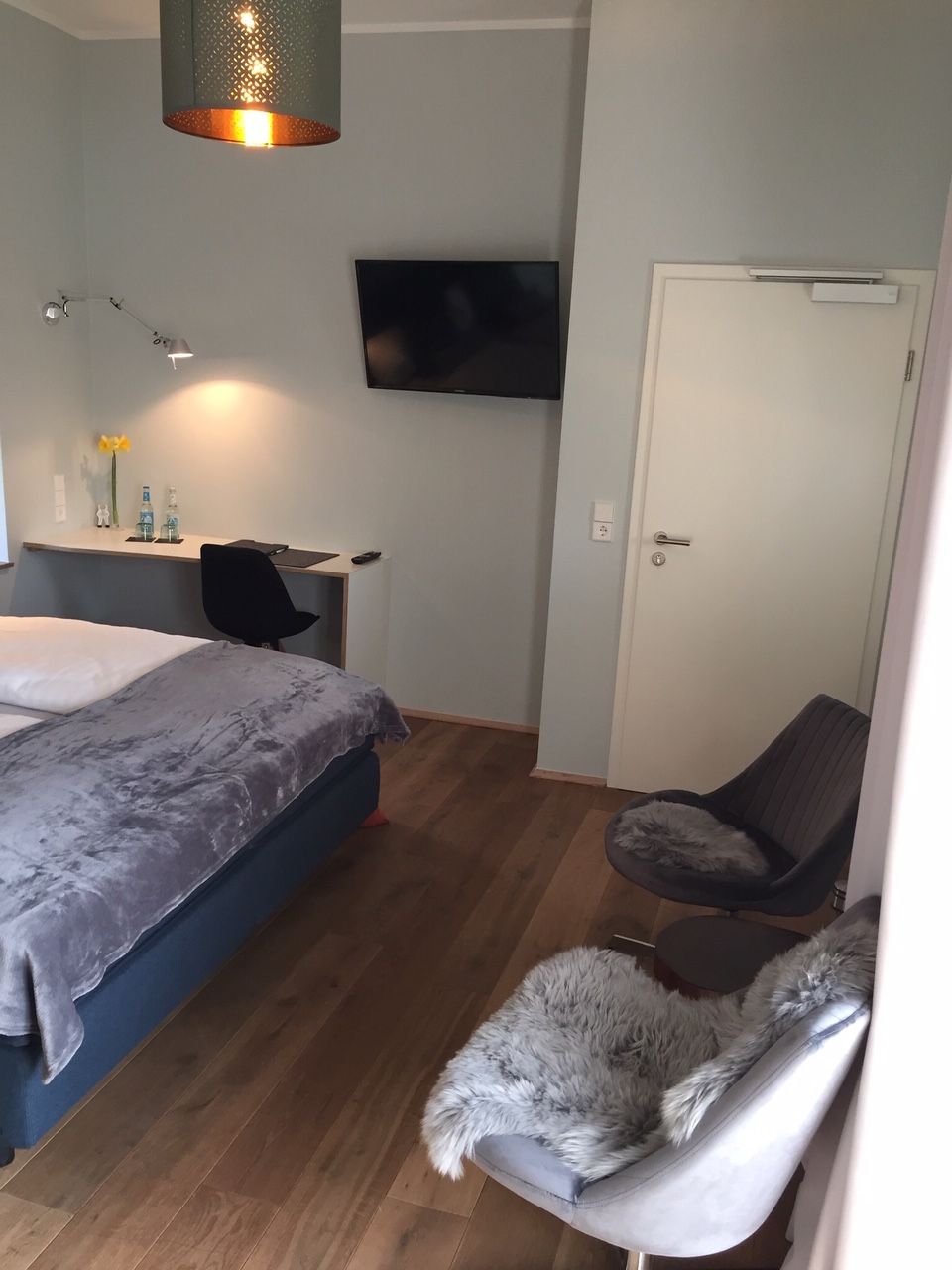 Une chambre à coucher avec un lit, un bureau, une chaise, une télévision et une porte.