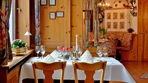 Un coin repas avec une table en bois dressée pour quatre personnes, un lustre et un canapé en arrière-plan.