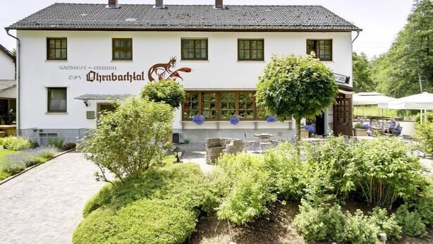 Un bâtiment sur lequel on peut lire l’inscription « GASTHAUS - Pension ZUHAUS » et qui arbore un logo représentant un écureuil roux.