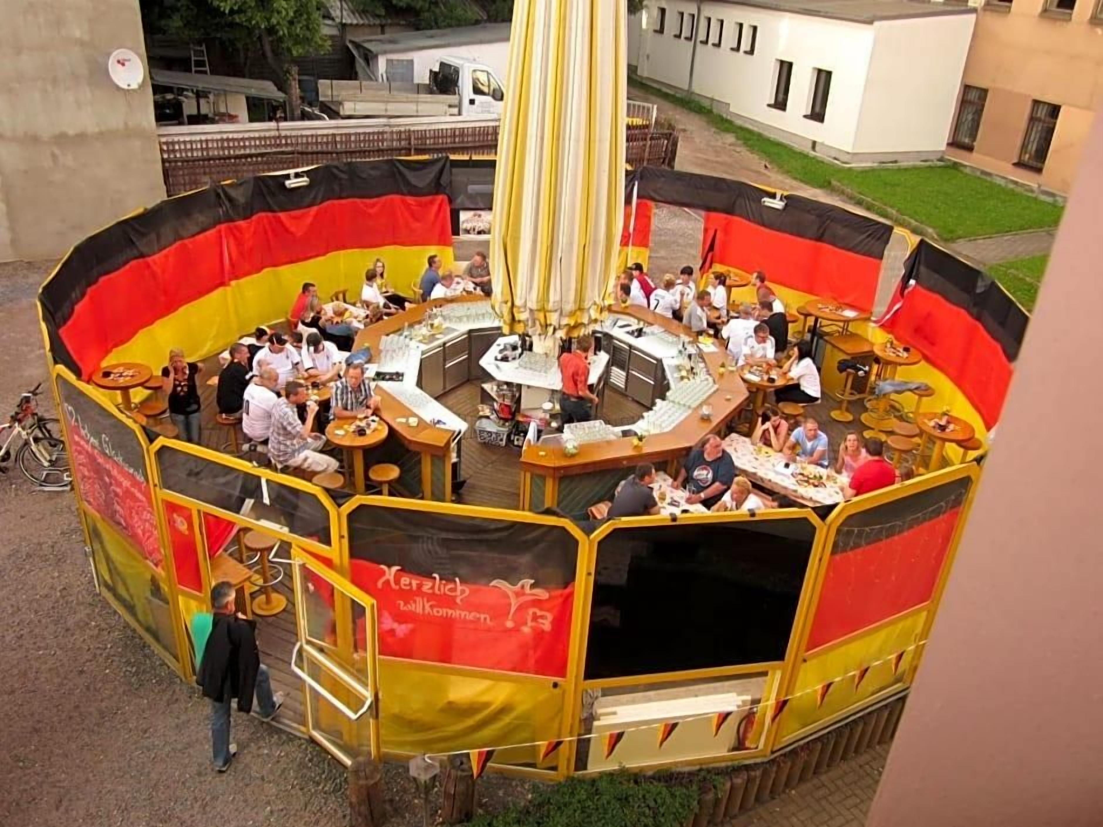 A circular outdoor dining area with multiple tables and chairs, surrounded by a yellow and red barrier.