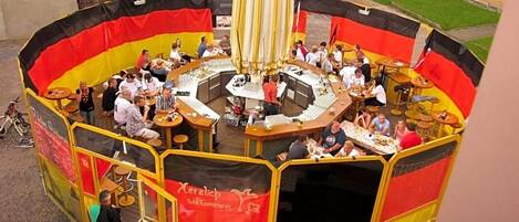 A circular outdoor dining area with multiple tables and chairs, surrounded by a yellow and red barrier.