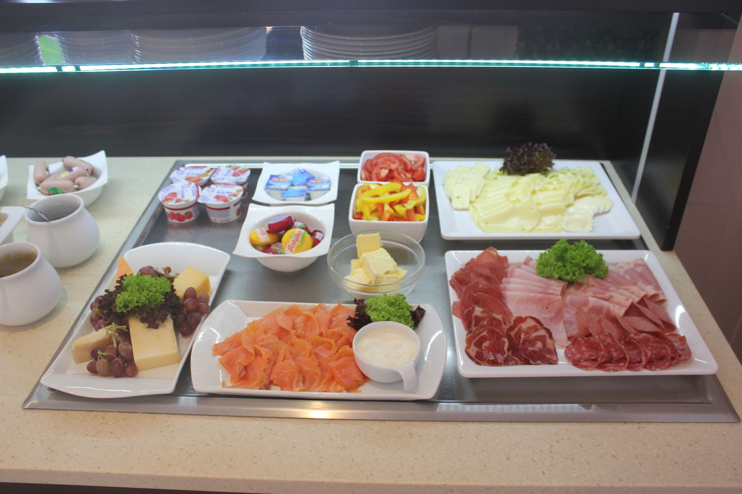 Buffet com diversos alimentos, incluindo queijo, salmão, carnes e vegetais.