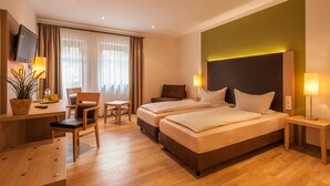 A hotel room with two beds, a desk, a chair, a TV, and a plant. - Hotel-Gasthof Weißes Roß (Kleinostheim)