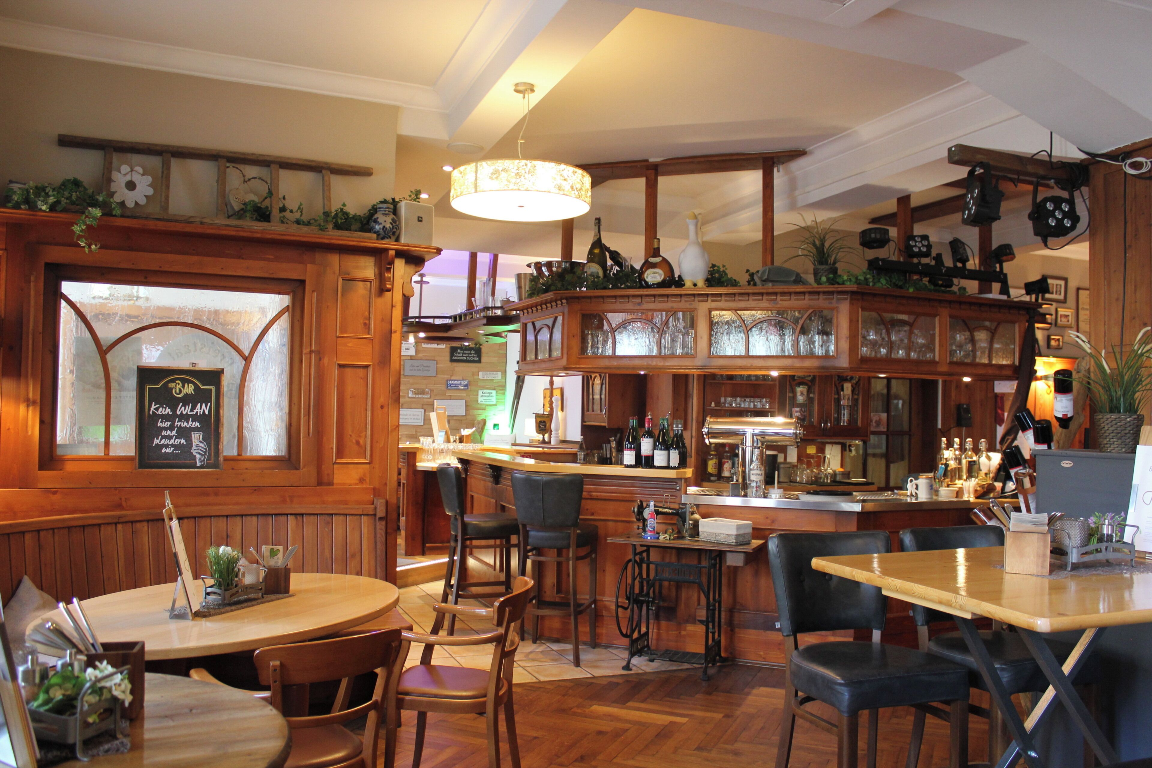 A bar area with wooden furniture, a bar counter, and various bottles and glasses.