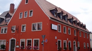 A red building with multiple windows, a sign indicating a hotel, and flower boxes on the windowsills. - Hotel-Gasthof Weißes Roß (Kleinostheim)