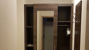 A hallway with a wooden wardrobe, a mirror, and a door with a towel rack. - Hotel-Gasthof Weißes Roß (Kleinostheim)