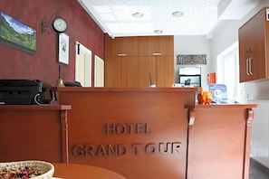 Un mostrador de recepción de hotel con un reloj y cuadros en la pared.