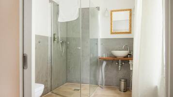 A modern bathroom with a glass-enclosed shower, a white sink, and a mirror on the wall.